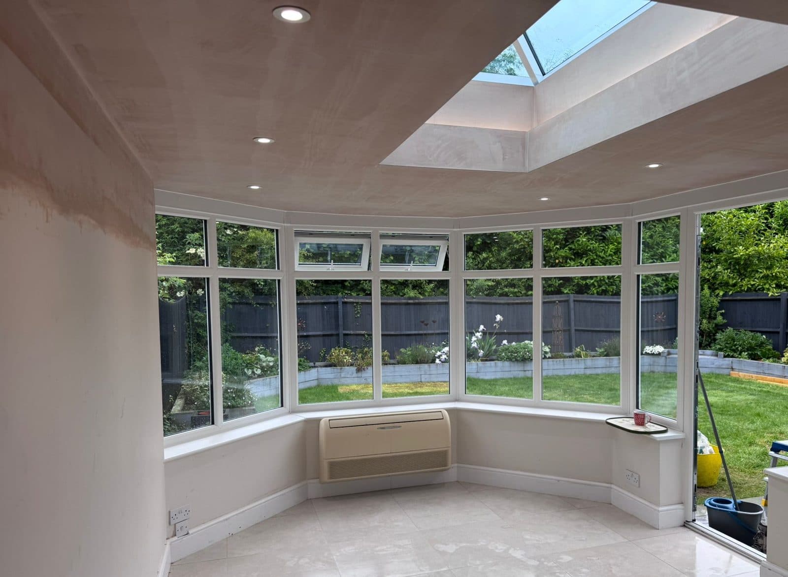 Bright conservatory interior with a bay window, roof lantern and garden view