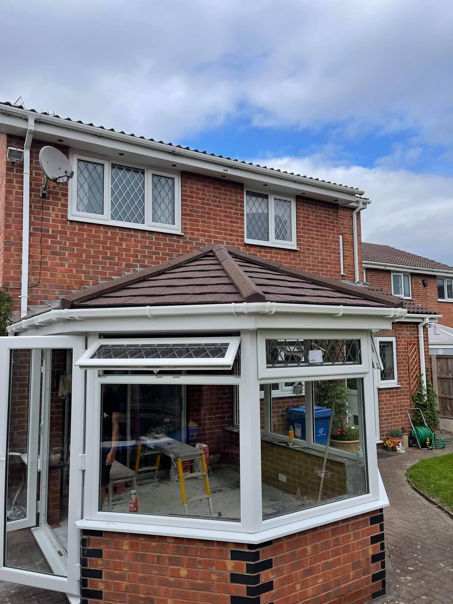 Conservatory with a new brown tiled warm roof and white frames