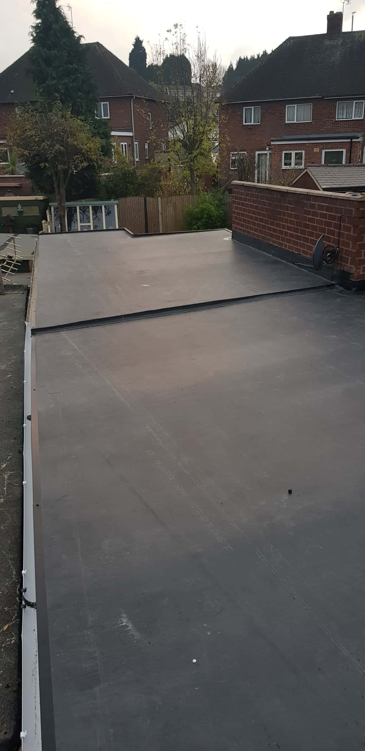 Completed grey flat roof installation on residential extension with white fascia trim