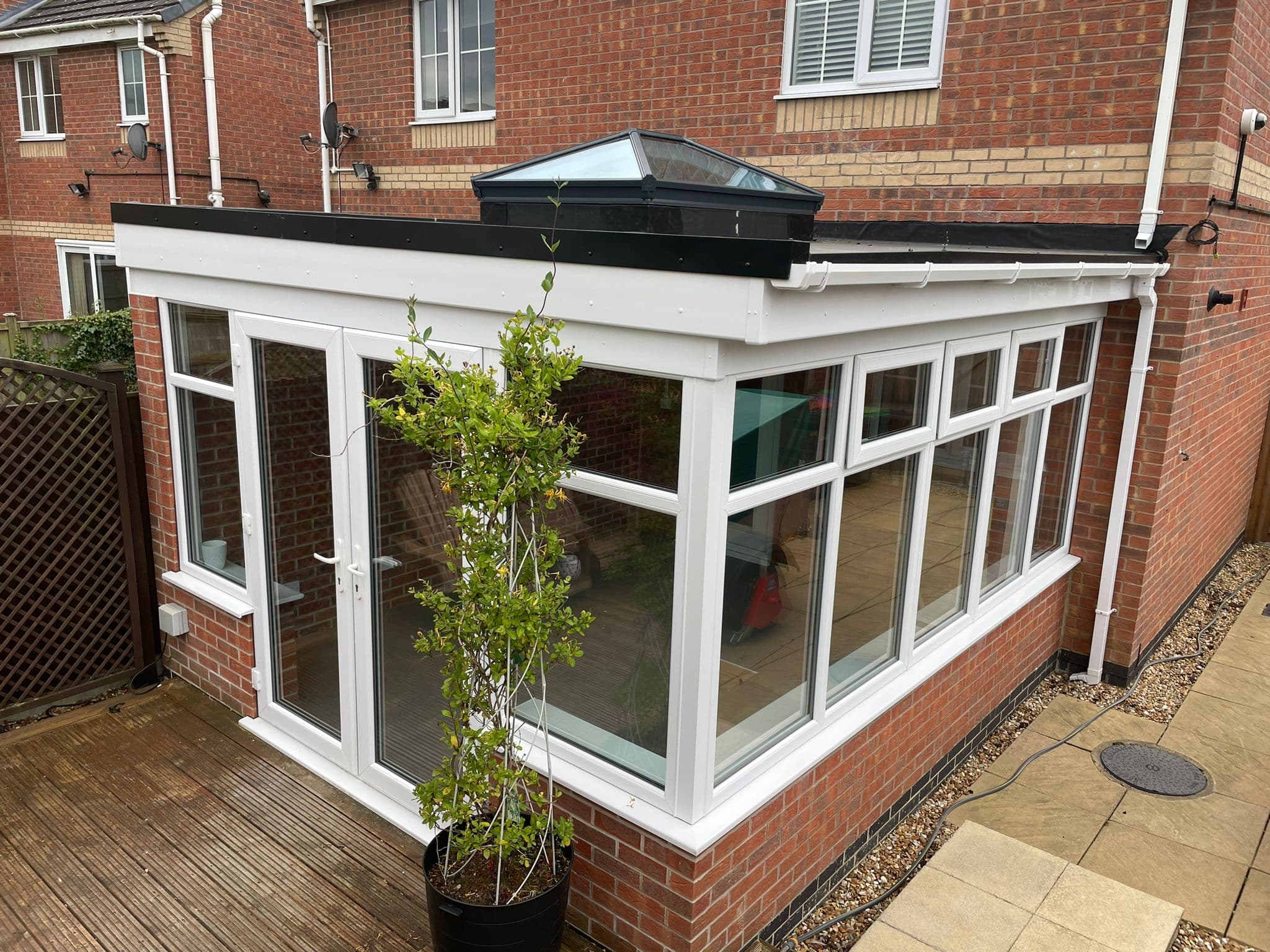 Conservatory with a new anthracite warm flat roof and glass roof lantern, exterior view in Skegby