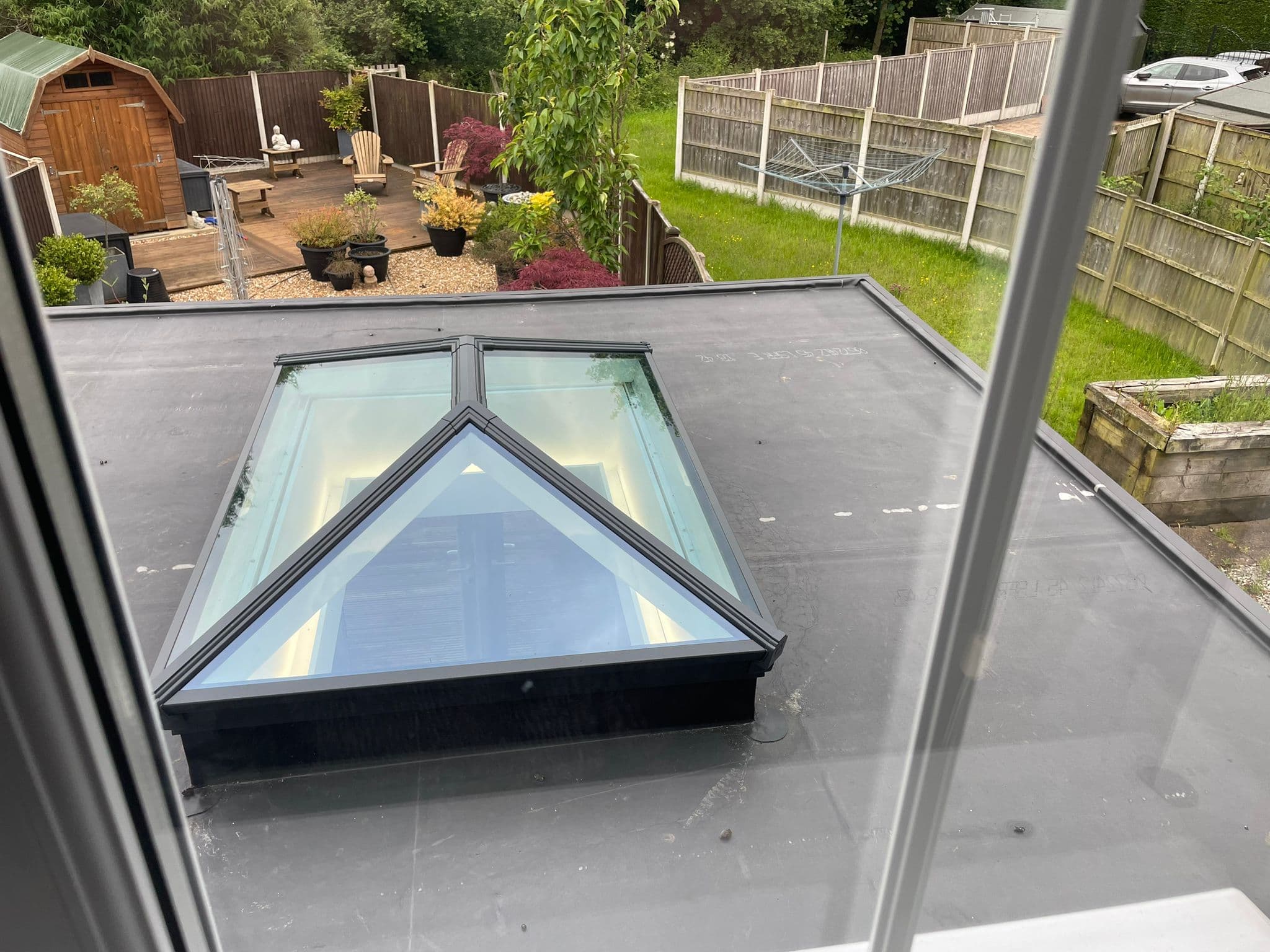 Glass pyramid roof lantern set into the new grey warm flat roof, viewed across the roof deck