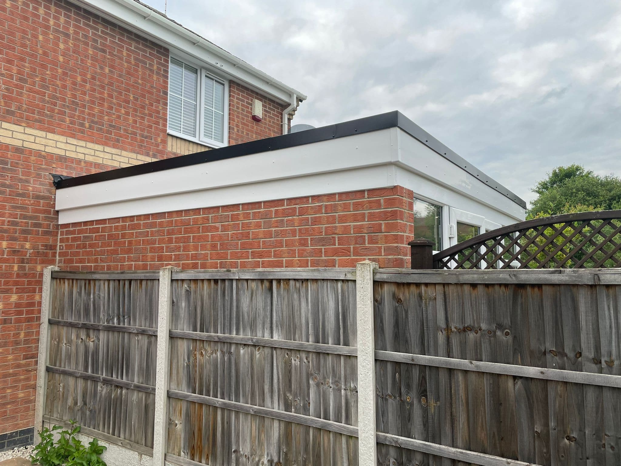 Exterior corner showing the white fascia and slim anthracite flat-roof edge